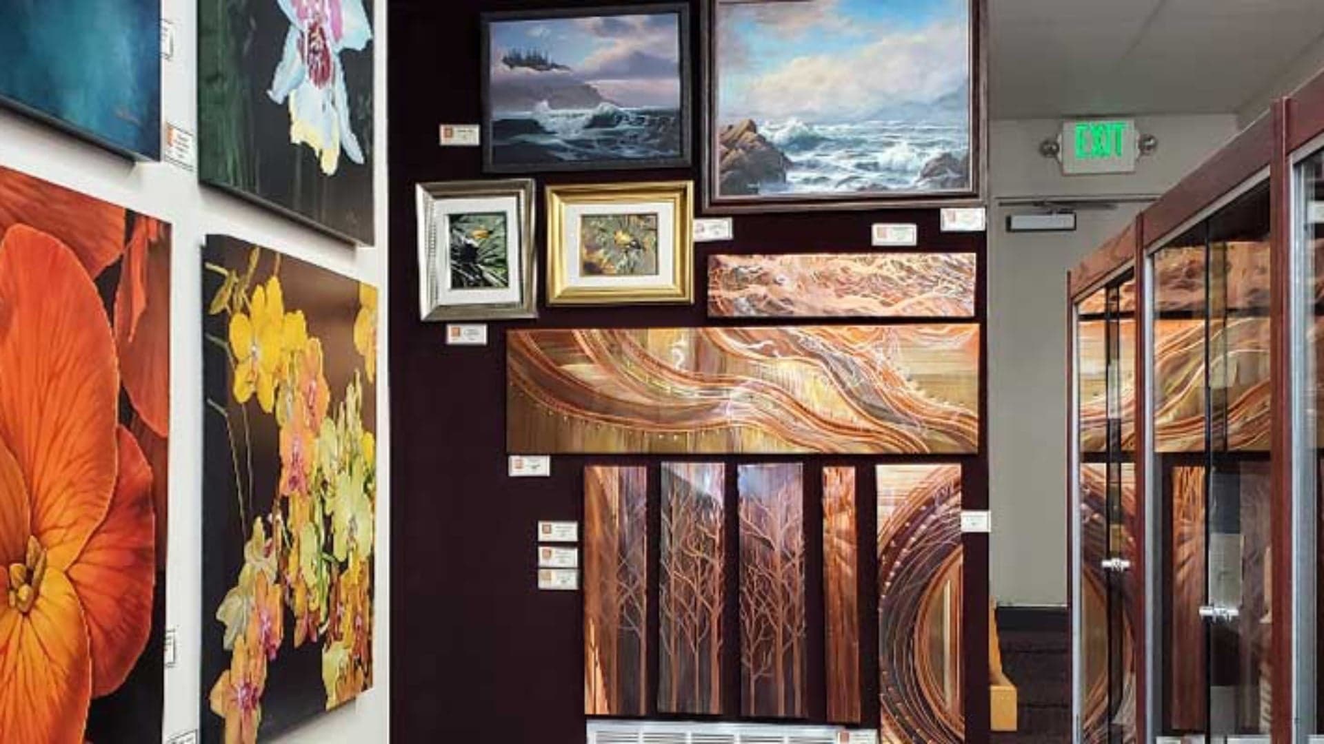 Gallery wall displaying various framed artworks, including florals, landscapes, and abstract designs.
