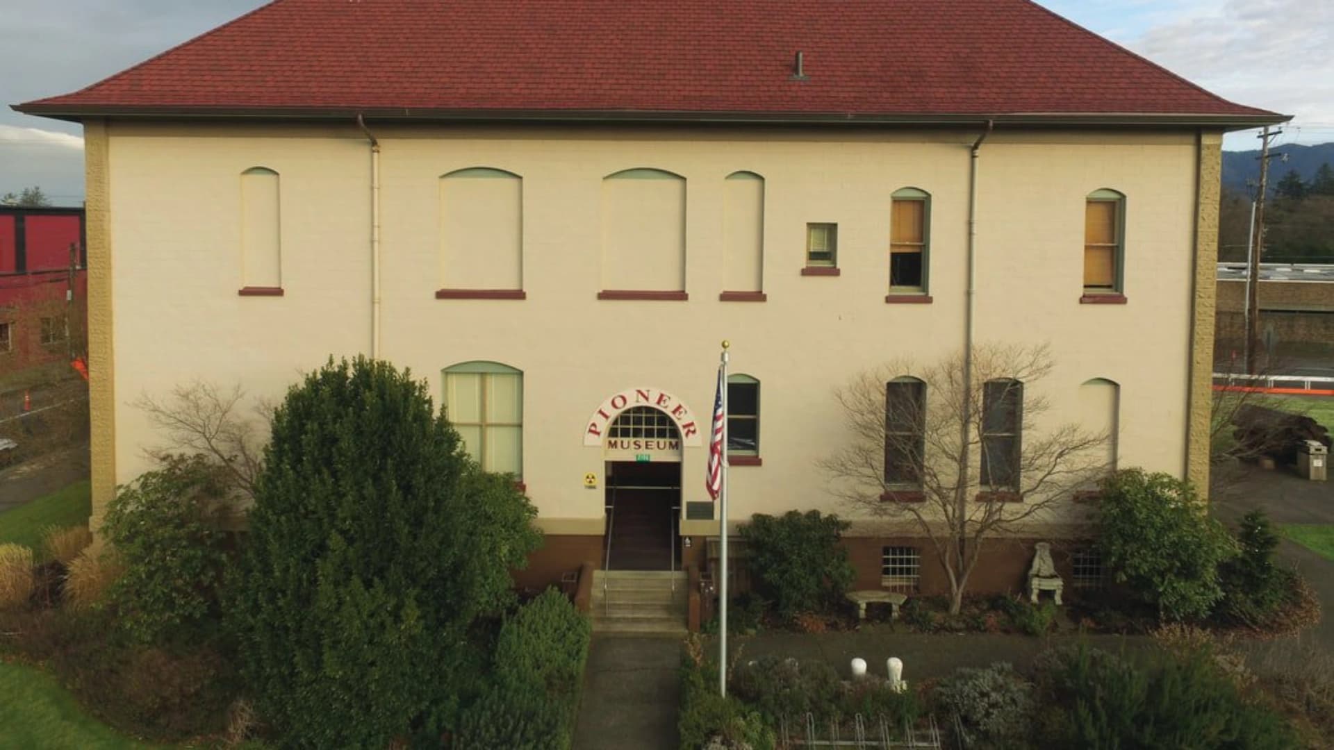 The Pioneer Museum building with a red roof, entrance stairs, and greenery in front.