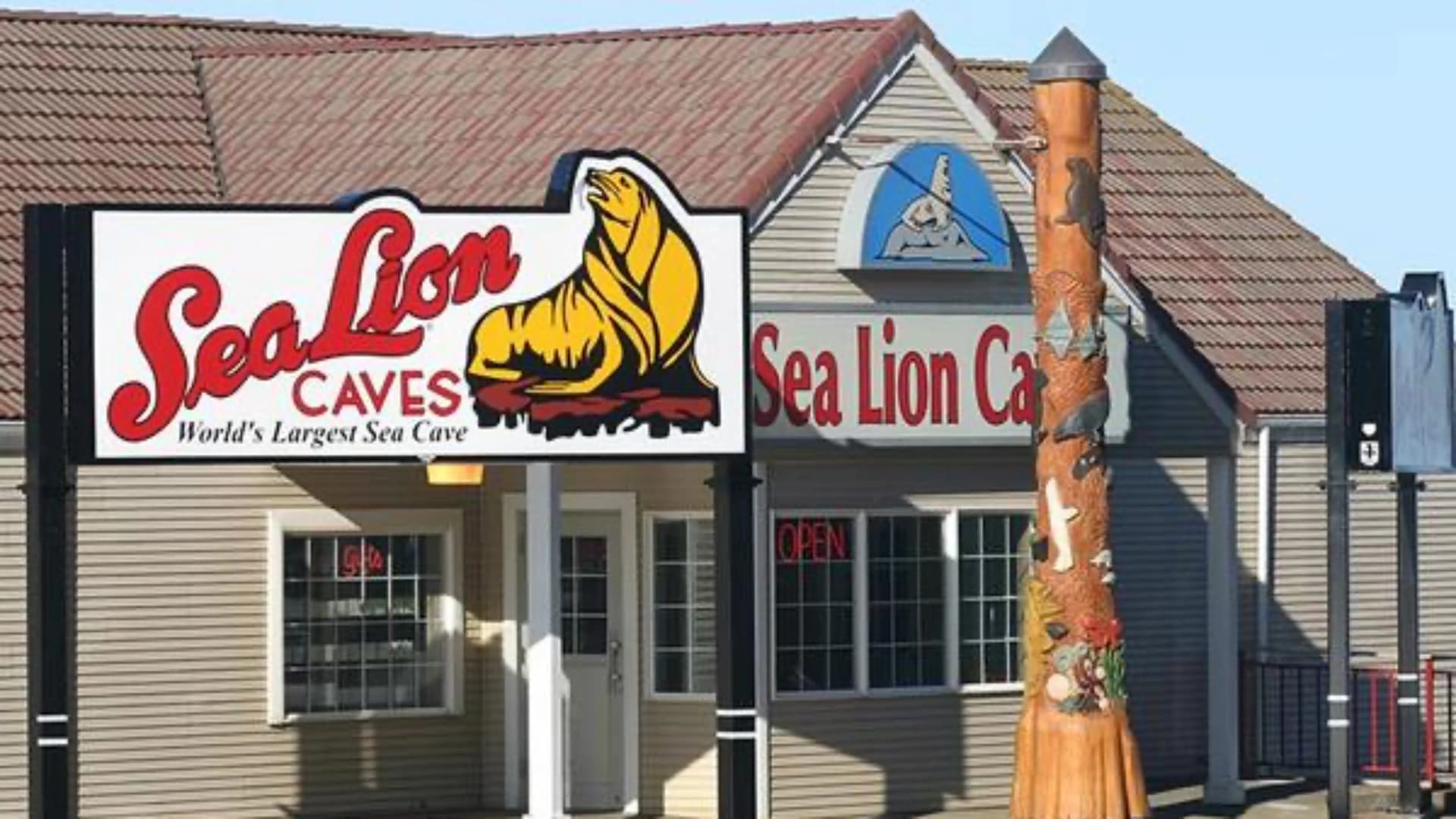 Sign for Sea Lion Caves with a large sea lion graphic, and a totem pole decorated with marine life.