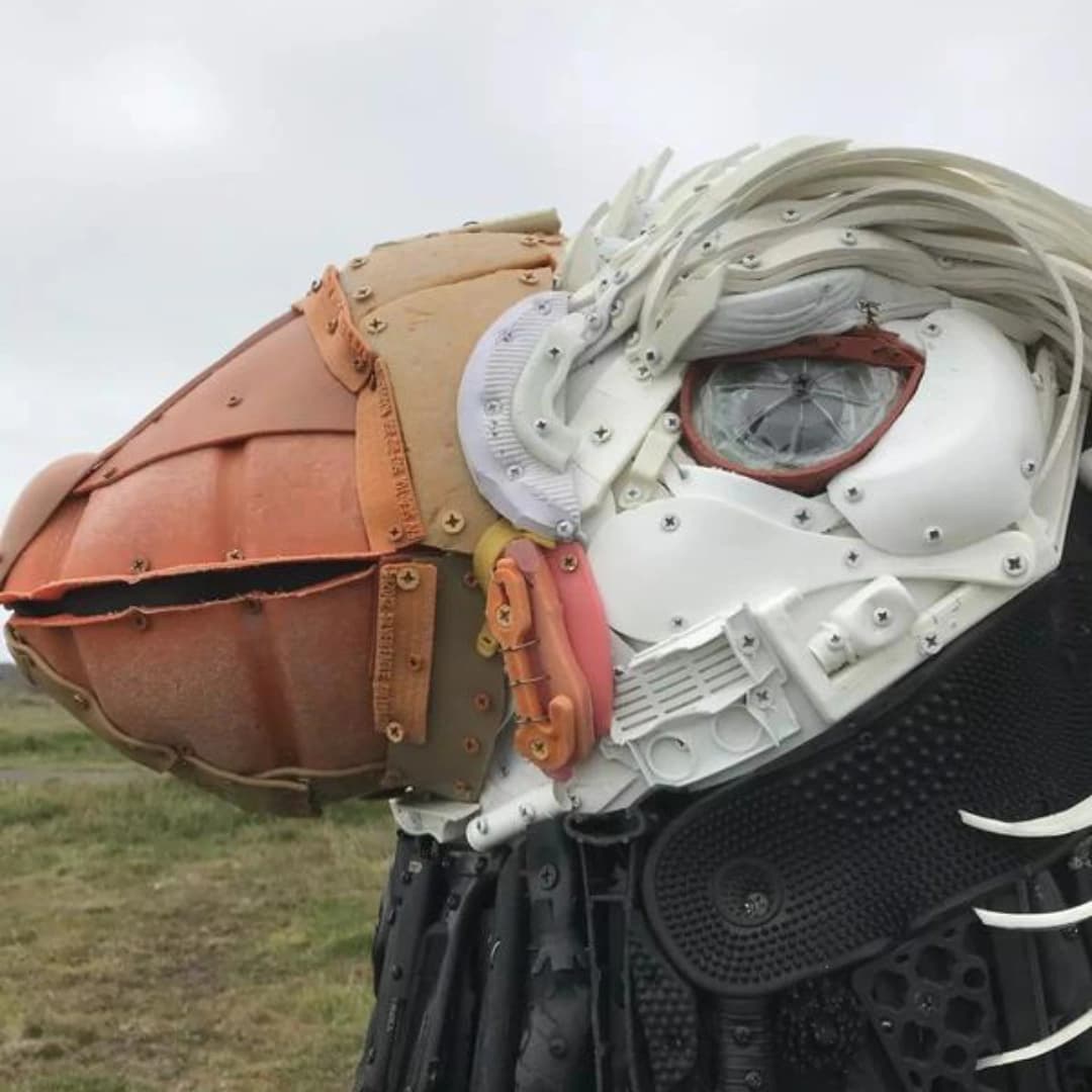Close-up of a large, intricate sculpture resembling a bird's head, made from various colored plastic materials.
