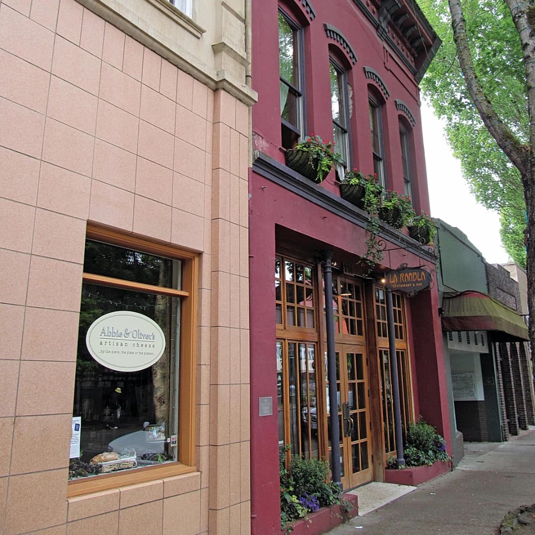 Facade of two buildings: a pink-tiled shop window on the left and a red restaurant entrance on the right, with planters.