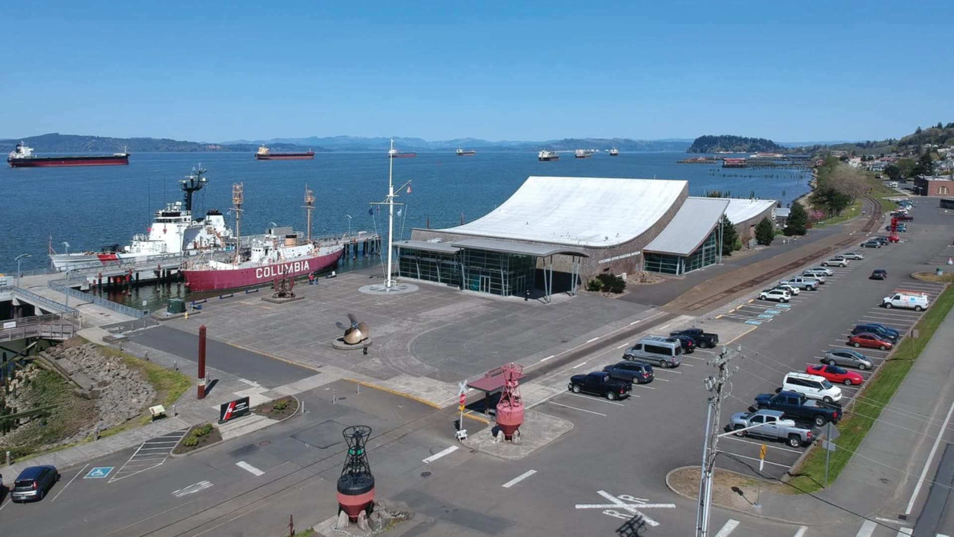 Aerial view of a dock with the ship "Columbia," coastal buildings, and parked cars along the waterfront.