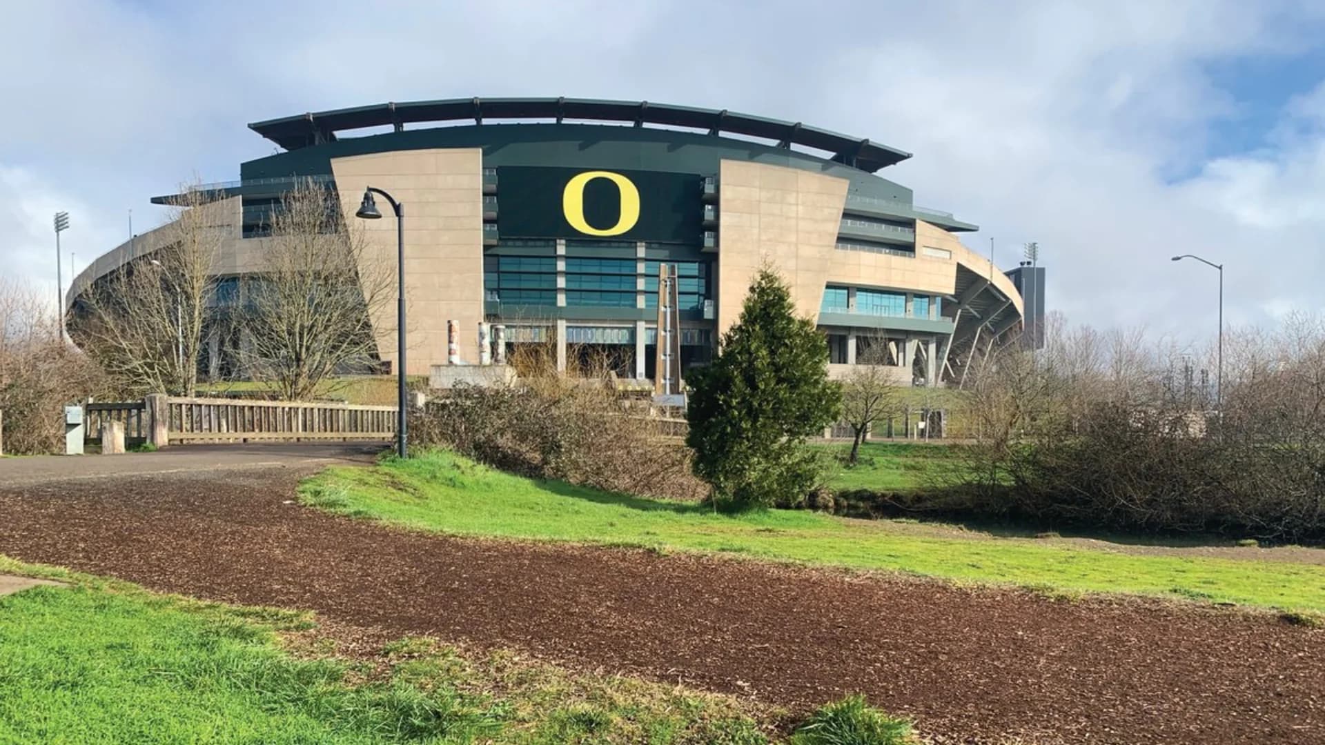 Autzen Stadium in Oregon, featuring a large "O" logo, surrounded by greenery and trees.